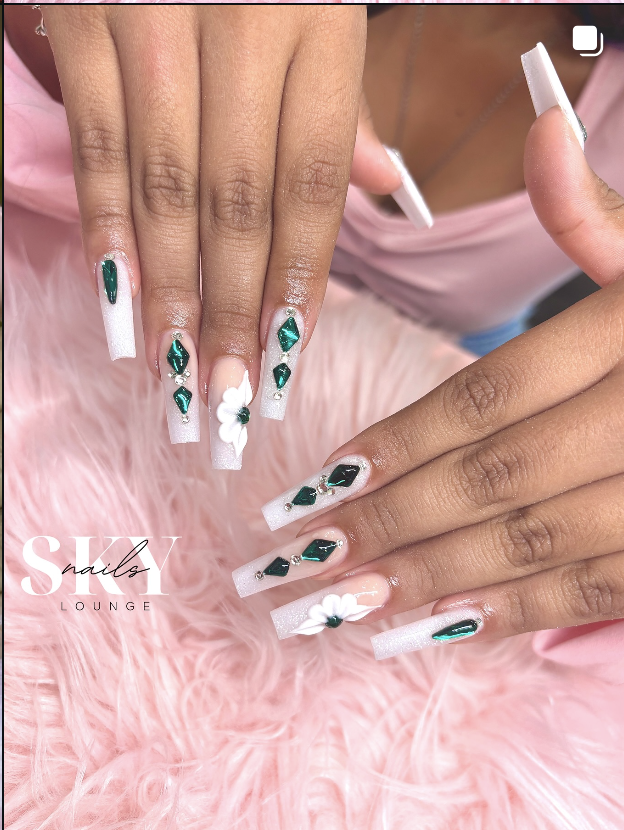 White nails with emerald gem accents and flowers
